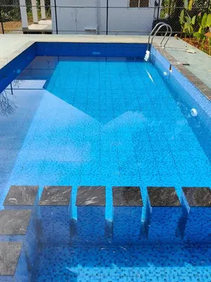 a swimming pool with blue tiles on top of it at Thoniyot Heritage villas in Kalpetta
