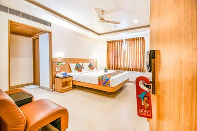 a hotel room with a bed and a chair at FabHotel Prime Royal Castle - Nr Coimbatore North Railway Station in Coimbatore