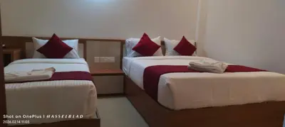 a bedroom with two beds with red and white sheets at Hotel Eden Palace in Trichūr