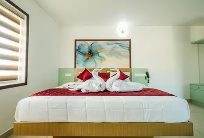 a bedroom with a bed with two white shoes on it at Hotel Eden Palace in Trichūr
