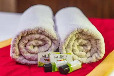 a pair of towels and a bottle of medicine on a bed at Blue Bell Hotel in Nedumbassery
