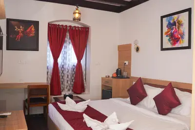 a bedroom with a bed with red curtains and a desk at Hotel Chithrapuri in Parli