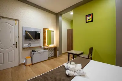 a hotel room with a bed and a tv at Paradise Point Ooty in Ooty
