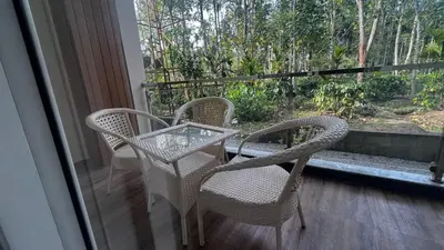 three chairs and a glass table on a balcony at Lotus Exotica Homestay in Suntikoppa