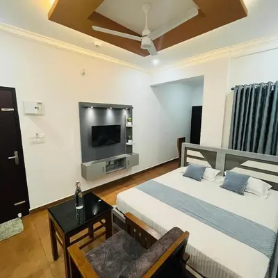 a hotel room with two beds and a tv at Enroute Delight Residency in Kotamangalam