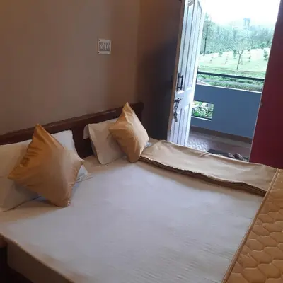 a bed with white sheets and pillows next to a window at River View Homestsy in Vālpārai
