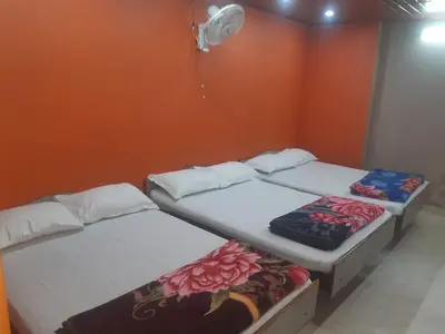 two beds in a room with an orange wall at River View Homestsy in Vālpārai