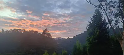 a sunset over a mountain with trees in the foreground at Jungle view in Coonoor