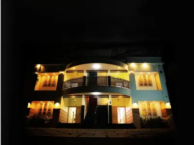 a large white building with a balcony at night at Aqualuxe Premium Suites in Vythiri