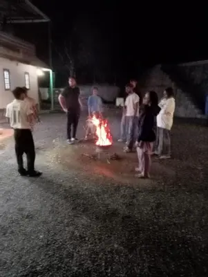 a group of people standing around a fire at night at Naduthotty Holiday Home in Viripara