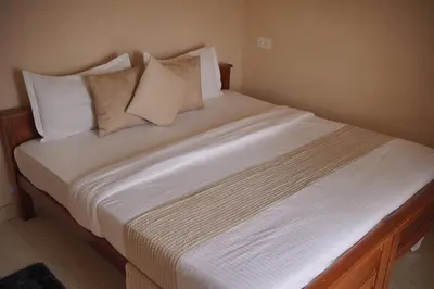 a bed with white sheets and pillows in a room at Mellowlux Ooty in Ooty