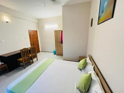 a bedroom with a bed and a table and a chair at Marhaba inn in Kozhikode