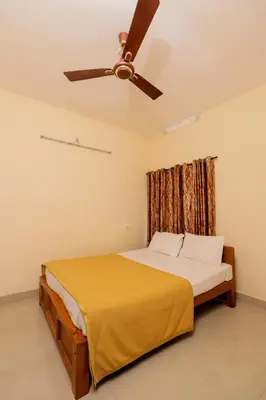 a bedroom with a bed with a ceiling fan at sky blue villa in Vythiri