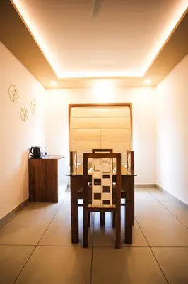 a dining room with a table and a chair at AJ Wayanad Suites in Kalpetta