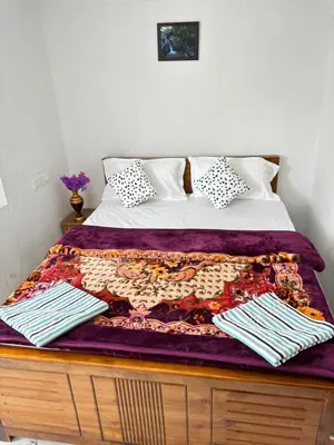 a bed with a purple blanket on top of it at Crown Crest in Ooty