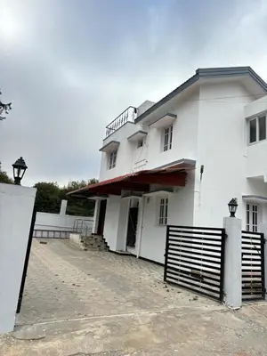 a white house with a gate in front of it at Crown Crest in Ooty