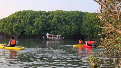 three people in kayaks on a river with a boat at Thiruthi Homestay in Vallikunnu