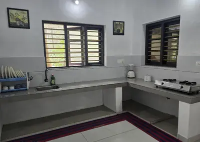 a kitchen with a counter and a sink and windows at Thiruthi Homestay in Vallikunnu