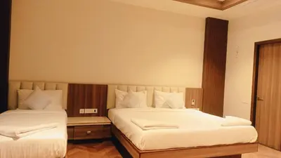 a bedroom with two beds with white sheets at Hotel Vintage Classic in Coimbatore