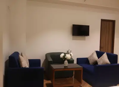 a living room with two blue chairs and a table at Hotel Vintage Classic in Coimbatore