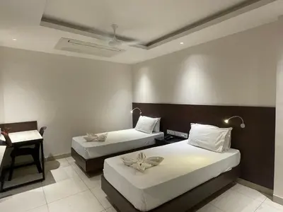 a hotel room with two beds and a desk at SV Grand in Mettuppālaiyam