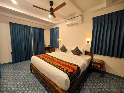 a bedroom with a large bed with blue curtains at Ibex Resorts, Coimbatore Kakarla in Alāndurai