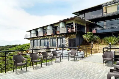 a house with a balcony with chairs on a patio at Ibex Resorts, Valparai Tale Rock in Vālpārai
