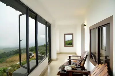 a living room with large windows with a view at Ibex Resorts, Valparai Tale Rock in Vālpārai