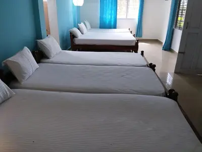 a group of four beds in a room at Mountain View Villas in Madikeri