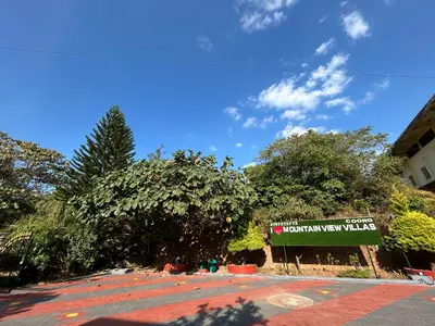 a sign in front of a building with trees at Mountain View Villas in Madikeri