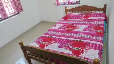 a bed with a pink and white quilt on it at Aswathy Bhavan Near Star auditorium vadakkenchery in Palakkad