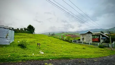 a green hill with a house and a grassy field at Away From Home - 6 - Home Stay Ooty, Entire 3BHK Villa in Ooty