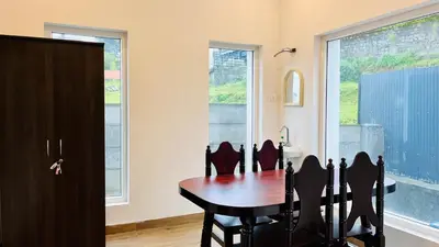 a dining room with a table and some windows at Away From Home - 6 - Home Stay Ooty, Entire 3BHK Villa in Ooty