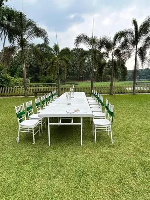 a long white table and chairs in the grass at Sparrow Vale Resort in Kotamangalam