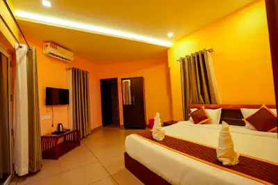 a hotel room with two beds and a television at Ginberry Holidays in Wayanad