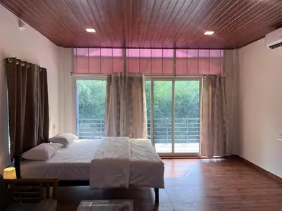 a bedroom with a bed and a large window at Rivana Homestay in Kushālnagar