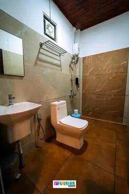 a bathroom with a toilet and a sink at Rivana Homestay in Kushālnagar
