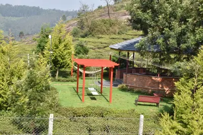 a red play structure in a yard with a bench at Green Nest Resort Ooty in Kotagiri