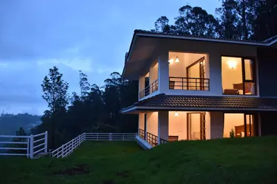 a house on a hill with the lights on at Green Nest Resort Ooty in Kotagiri