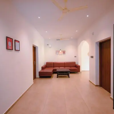 a living room with a couch and a table at Ohstayz Villa De Estate 64 in Kizhake Chālakudi