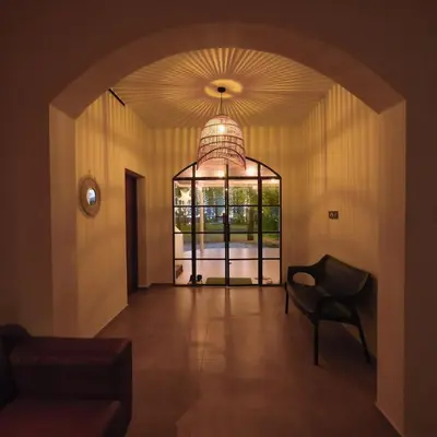 a hallway with a chair and a large window at Ohstayz Villa De Estate 64 in Kizhake Chālakudi