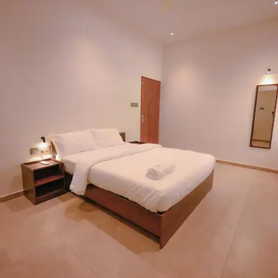 a bedroom with a large bed and a night stand at Ohstayz Villa De Estate 64 in Kizhake Chālakudi