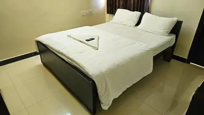 a bed with white sheets and a tray on it at Rodas Serviced Apartment in Coimbatore