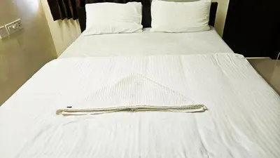 a white bed with a white blanket on it at Rodas Serviced Apartment in Coimbatore