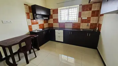 a small kitchen with a table and a sink at Rodas Serviced Apartment in Coimbatore
