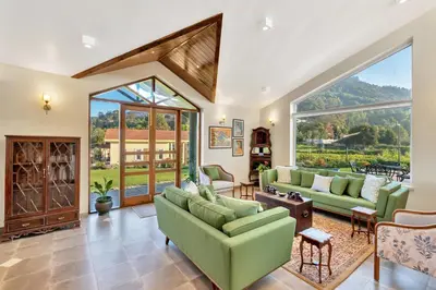 a living room with green furniture and large windows at SaffronStays Coonoor Canvas in Coonoor