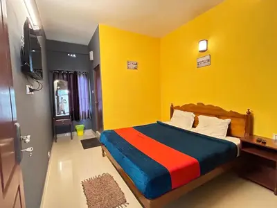 a bedroom with a bed with a yellow wall at Munnar House in Munnar