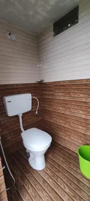a bathroom with a toilet in a wooden wall at Mount Camp in Marayoor