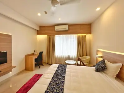 a hotel room with a bed and a desk and a window at Hotel Amaravathi BY D2V in Manattala