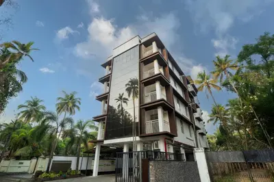 a building with palm trees in front of it at Daan Temple Inn in Guruvāyūr
